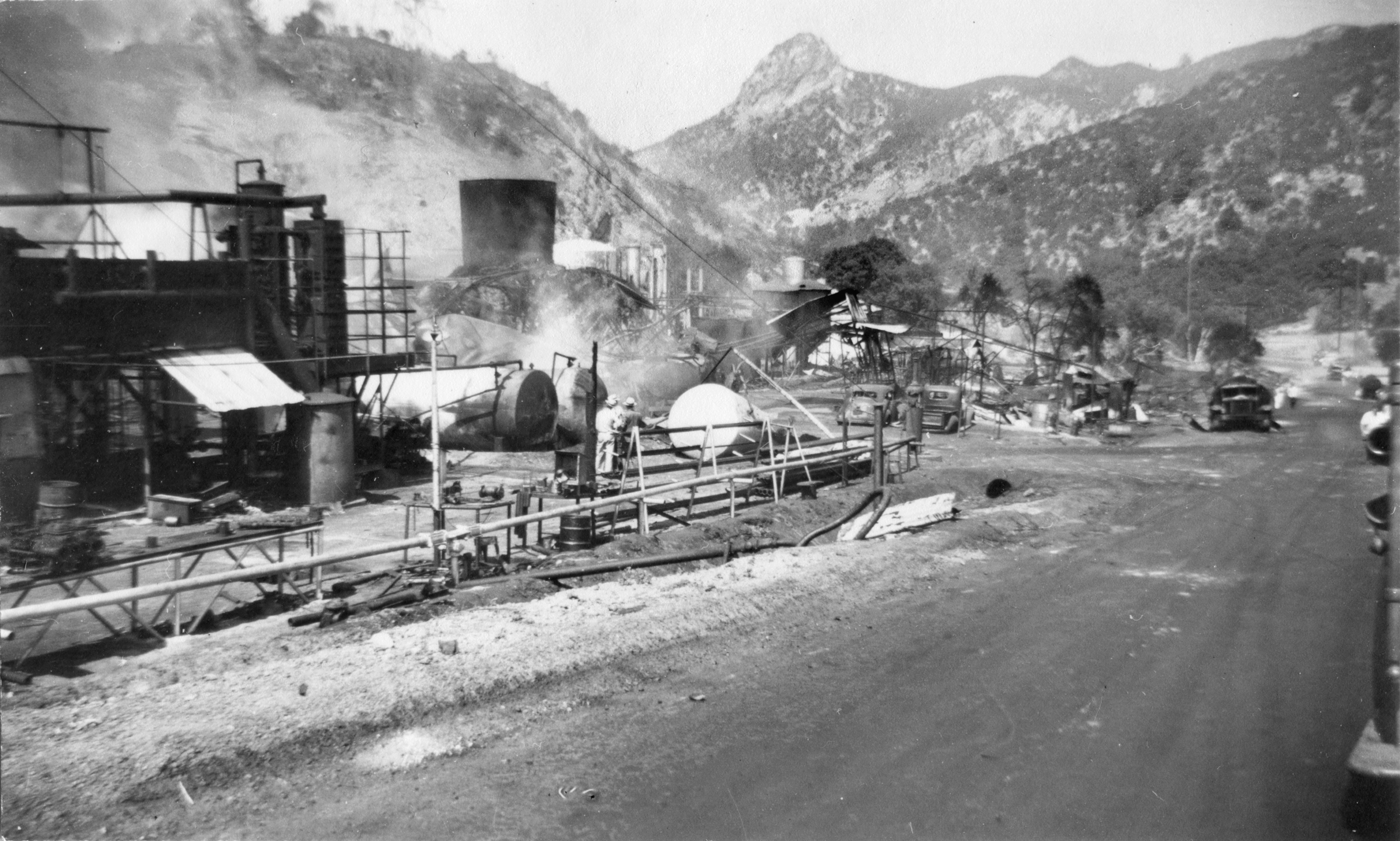 Newhall Refinery in 1944 after an explosion, with a fallen storage tank and workers looking on